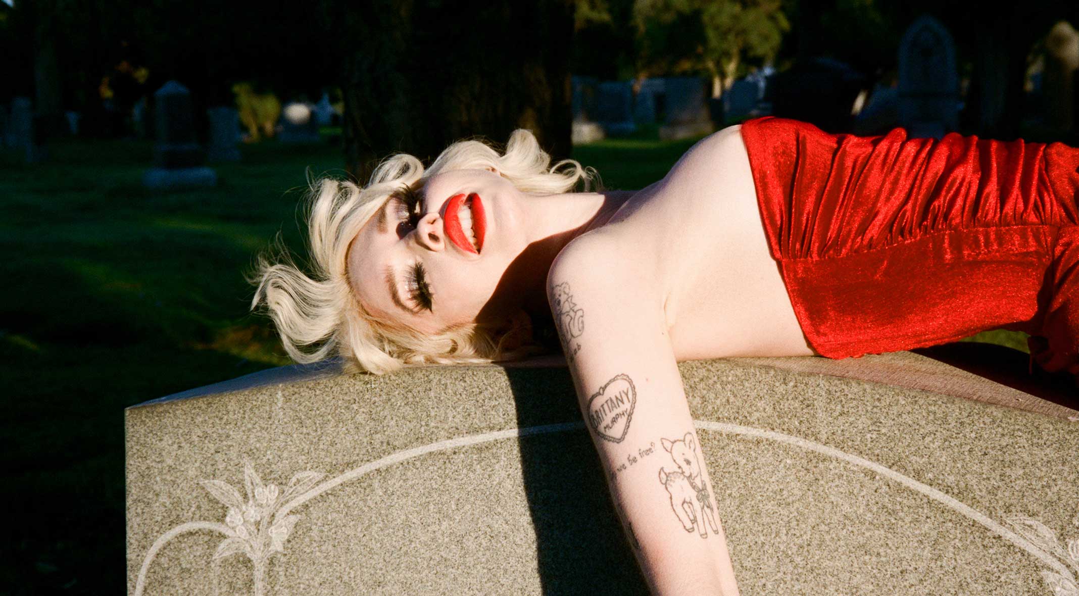 Glüme on a headstone in a red dress